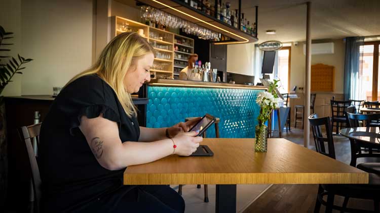 UNE PERSONNE BLONDE AVEC UN IPAD DANS LES MAIN ENTREIN DE FAIRE LA FORMATION DE GESTIONNAIRE DE BAR EN LIGNE