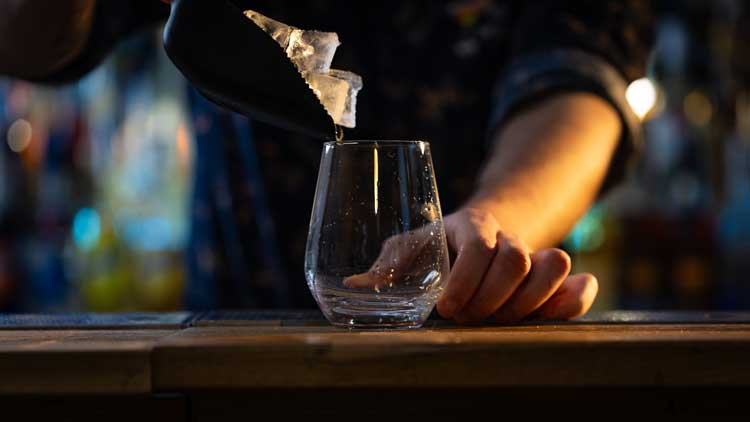 GLACONS PRESQUE DANS UN VERRE AVEC UNE PELLE A GLACONS POUR LES BARMANS OU BARTENDER