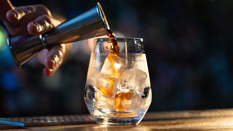 VERSE D'UN SPIRITIEUX DANS UN VERRE AVEC DES GLACONS